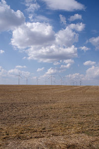 Wind turbines on field against sky