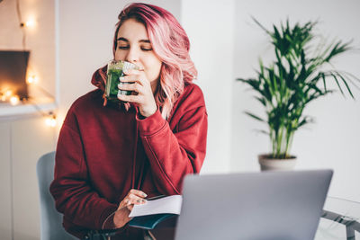 Young woman using mobile phone while sitting on table