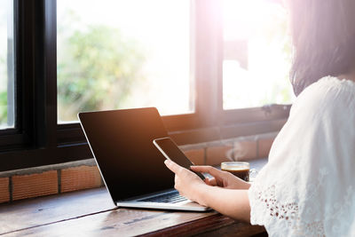 Close-up of woman using mobile phone at home