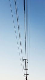 Low angle view of electricity pylon against blue sky