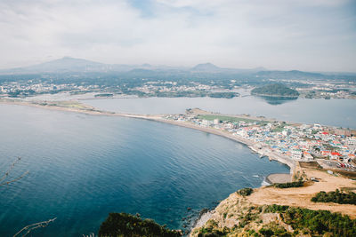 High angle view of city by sea against sky