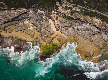 High angle view of sea waves hitting rock formations