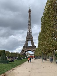 Group of people in front of tower against cloudy sky