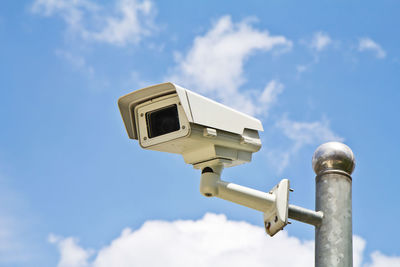 Low angle view of security camera on pole against sky