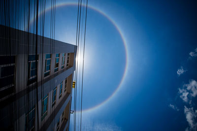 Low angle view of rainbow over building against sky