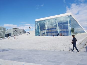 People walking on modern building against sky in city