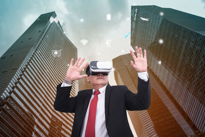 Businessman wearing virtual reality simulator against modern buildings