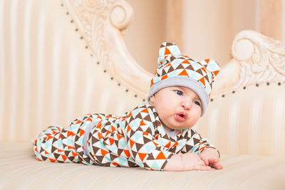 Close-up of cute baby girl on bed at home