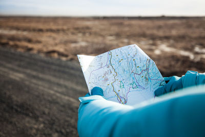 Close-up of hands holding map on road