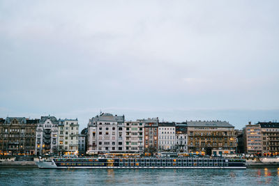 Sea by buildings in city against sky