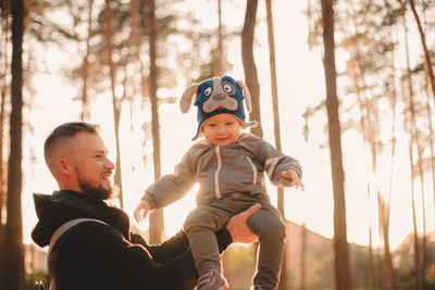 Happy father playing with son outdoors in park during sunny day