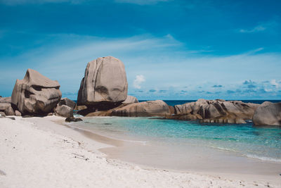 Rock formations on beach against sky