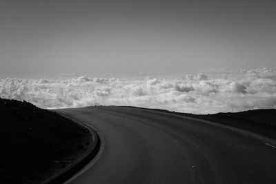 Empty road on mountain leading towards cloudscape