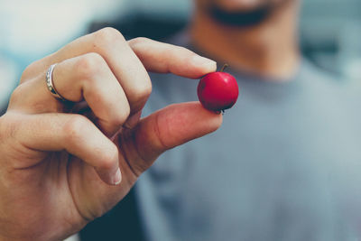 Midsection of man holding cherry