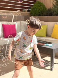 Side view of cute girl playing with arms raised sitting on sofa at home