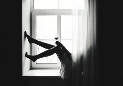 Woman looking through window at home