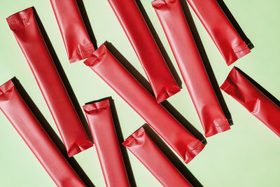 Red stick packs scattered on green. beverage packaging mockups and food product presentation.
