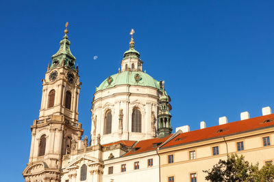 Low angle view of clock tower with the dome of st nicholas cathedral on lesser town square.