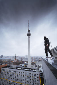 Man standing by modern buildings against sky