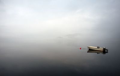 Boat moored in lake during foggy weather