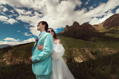 Young woman standing on mountain against sky