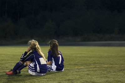 Rear view of girls relaxing on soccer field
