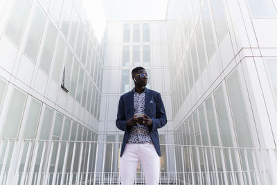 Low angle view of young man standing against building