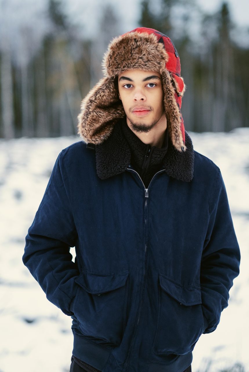 PORTRAIT OF HANDSOME YOUNG MAN STANDING IN SNOW