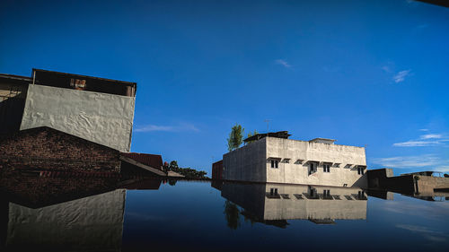 Reflection of buildings in lake against blue sky