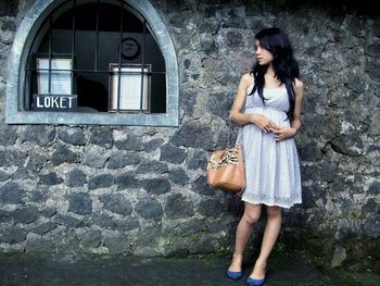 Full length of woman standing against wall