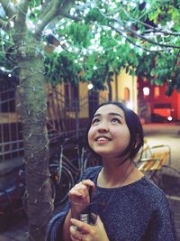 Smiling young woman looking up while standing outdoors