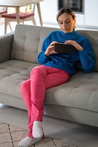 Young woman in blue sweater touches vr glasses for first time and wants to try playing games