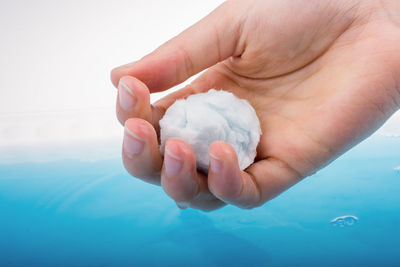 Cropped hand of person soaking cotton in blue water