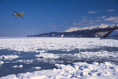 Scenic view of sea and snowcapped mountains against sky