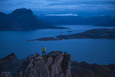 High angle view of man hiking on mountain against sea at dusk