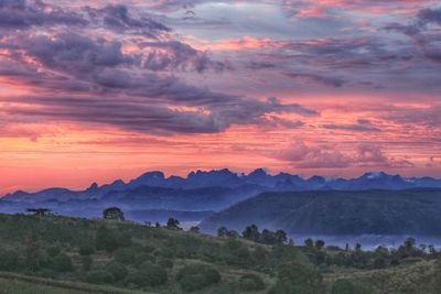 Scenic view of landscape against dramatic sky during sunset