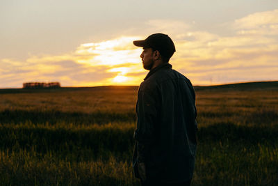 Man standing on field against sky during sunset