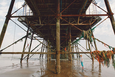 Woman standing below eastbourne pier at beach
