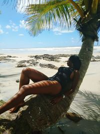 Seductive woman lying on tree trunk at beach