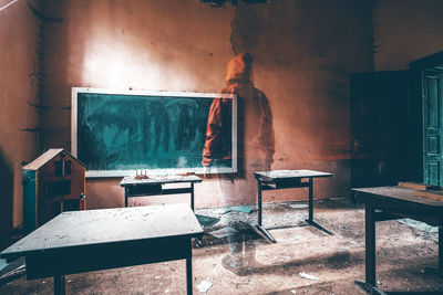 Empty chairs and table against wall