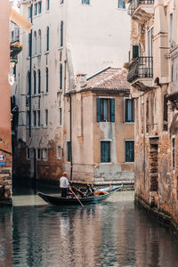 Boats in canal amidst buildings in city