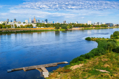 Scenic view of river by buildings against sky