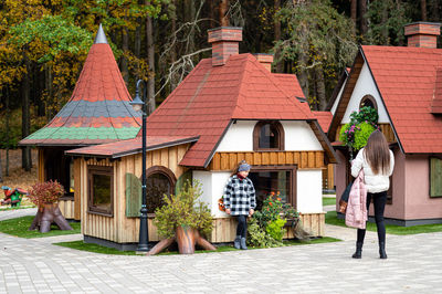 People walking on footpath amidst plants outside building