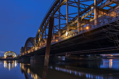 Illuminated bridge over river against sky at night