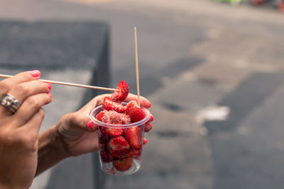 Cropped hands of woman eating strawberries