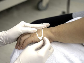 Cropped image of doctor applying bandage on patient hand