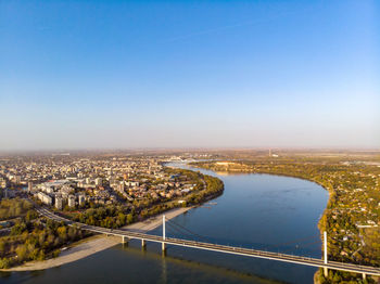 High angle view of river amidst buildings in city against clear blue sky