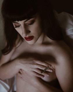 Shirtless young woman smoking cigarette