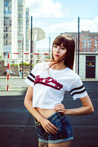 Young woman standing in city against sky