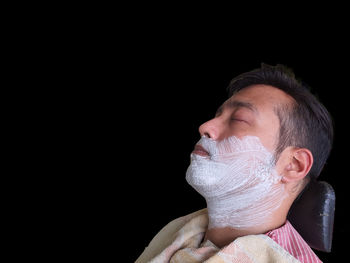 Close-up portrait of man against black background